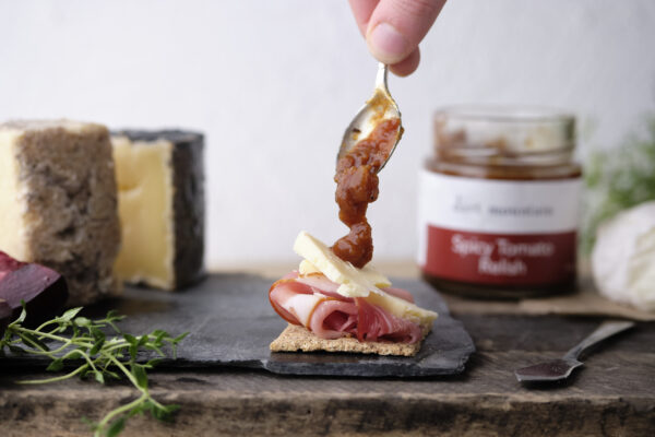 a serving of Dart Mountain Spicy Tomato Relish onto a cracker and cheese.